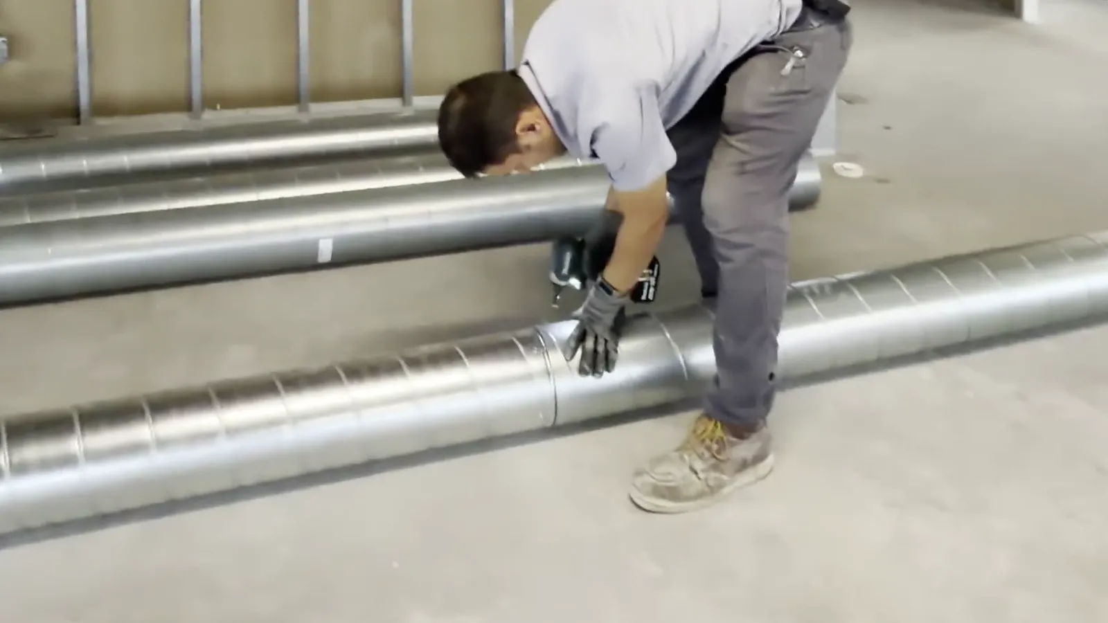 Houston AC Master technician assembling spiral supply duct on an office tenant finish in Houston